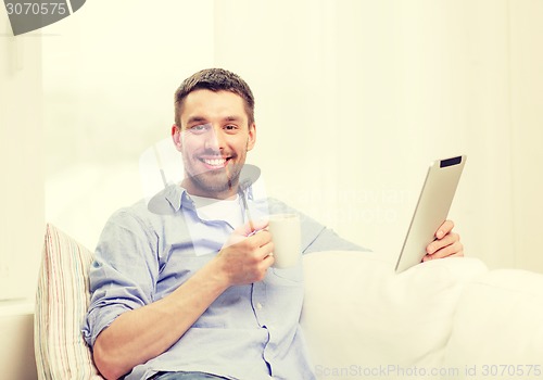 Image of smiling man working with tablet pc at home