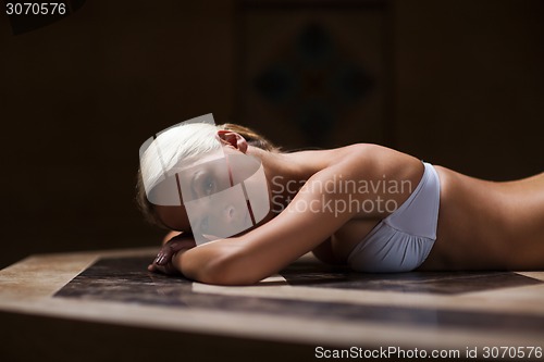 Image of young woman lying on hammam table in turkish bath