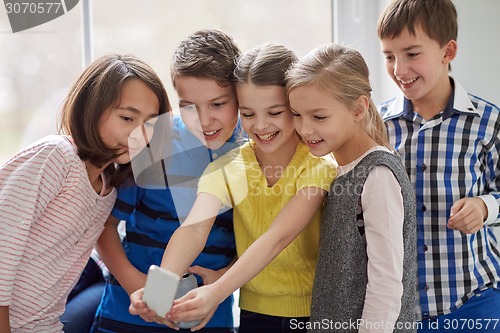 Image of group of school kids taking selfie with smartphone