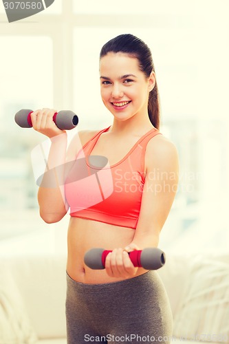 Image of smiling teenage girl exercising with dumbbells