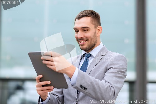 Image of smiling businessman with tablet pc outdoors