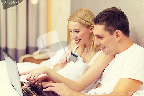 Image of couple in bed with laptop computer and credit card