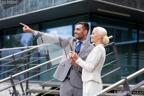 Image of smiling businessmen with tablet pc outdoors