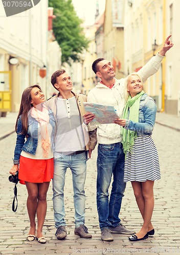 Image of group of smiling friends with map and photocamera