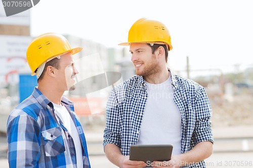 Image of smiling builders with tablet pc outdoors