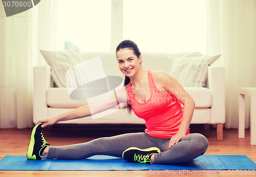 Image of smiling teenage girl streching on floor at home