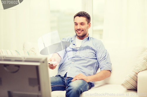 Image of smiling man with tv remote control at home