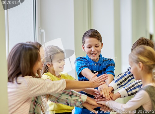 Image of group of smiling school kids putting hands on top