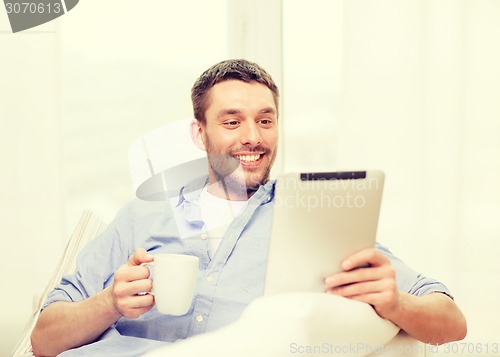 Image of smiling man working with tablet pc at home
