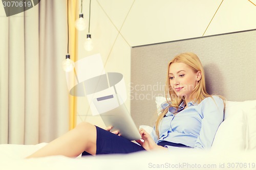 Image of happy businesswoman with tablet pc in hotel room