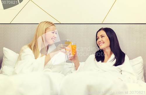 Image of smiling girlfriends having breakfast in bed