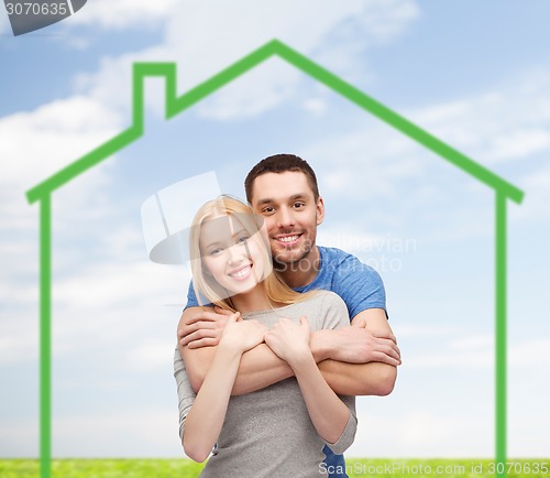 Image of smiling couple hugging over green house