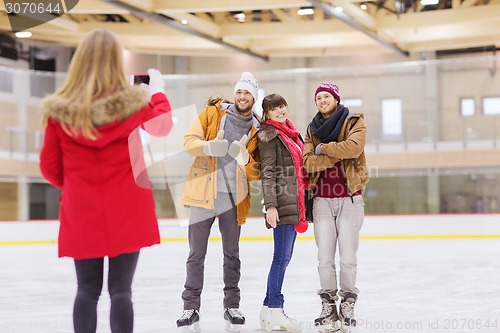 Image of happy friends taking photo on skating rink