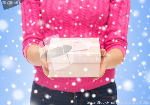 Image of close up of woman in pink sweater holding gift box