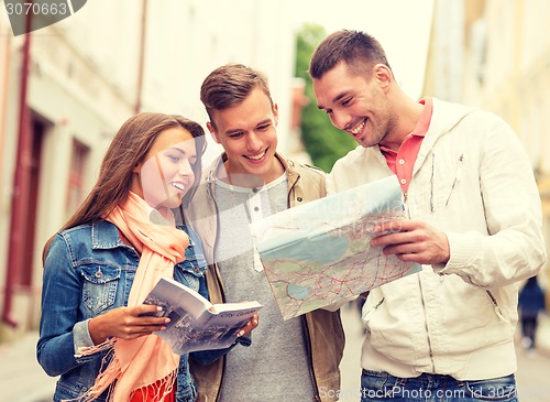 Image of group of smiling friends with city guide and map