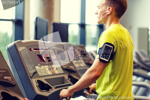 Image of man with smartphone exercising on treadmill in gym