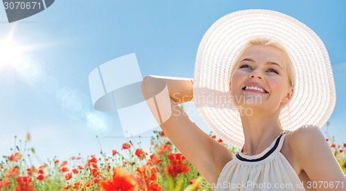 Image of smiling young woman in straw hat on poppy field