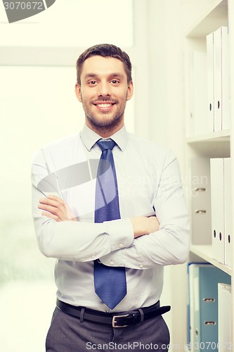 Image of handsome businessman with crossed arms at office