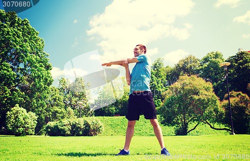 Image of smiling man stretching outdoors