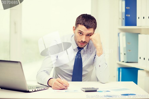 Image of stressed businessman with laptop and documents