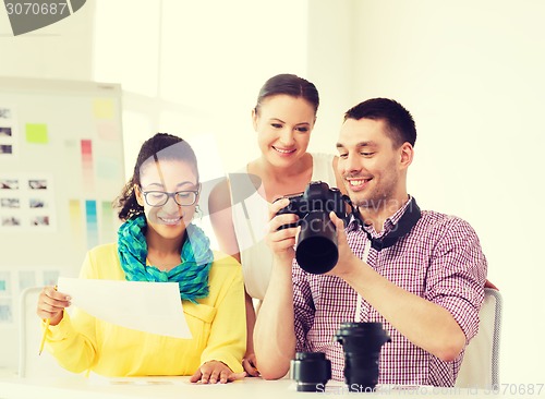 Image of smiling team with photocamera working in office