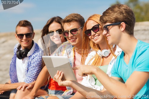 Image of group of smiling friends with tablet pc outdoors