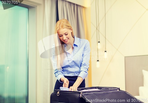 Image of businesswoman packing things in suitcase