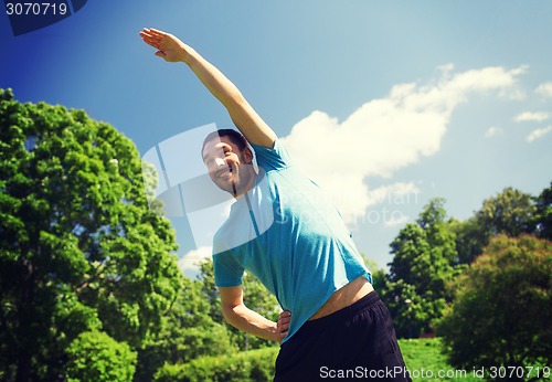 Image of smiling man stretching outdoors