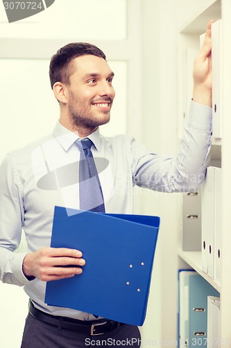 Image of handsome businessman picking folder at office