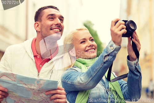 Image of smiling couple with map and photocamera in city
