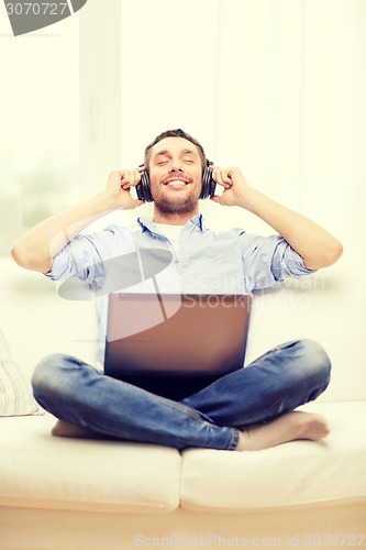 Image of smiling man with laptop and headphones at home