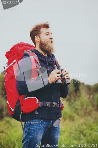 Image of smiling man with backpack and binocular outdoors