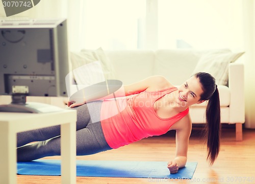 Image of smiling teenage girl doing side plank at home