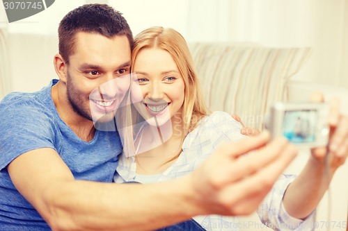 Image of smiling couple taking picture with digital camera