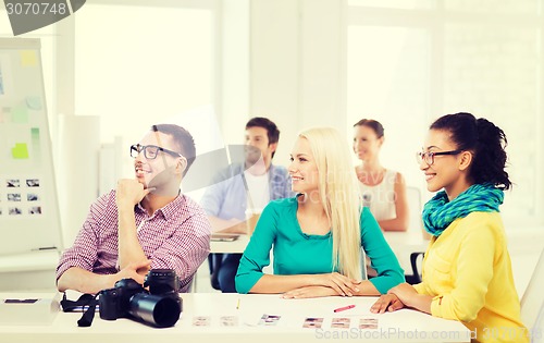 Image of smiling team with photocamera working in office