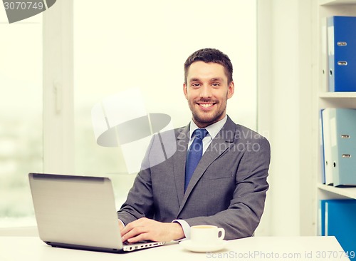 Image of smiling businessman with laptop and coffee