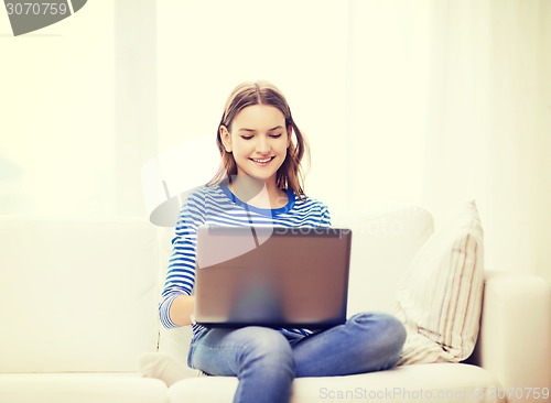 Image of smiling teenage girl with laptop computer at home