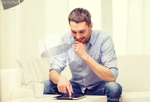 Image of smiling man working with tablet pc at home