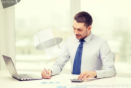 Image of smiling businessman with laptop and documents