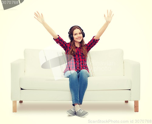 Image of teenage girl sitting on sofa with headphones