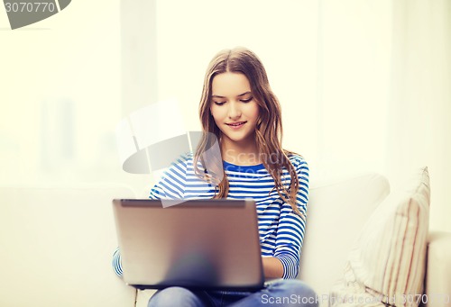 Image of smiling teenage girl with laptop computer at home