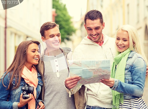 Image of group of smiling friends with map and photocamera