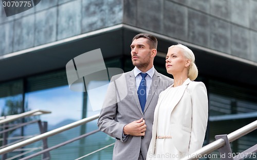 Image of serious businessmen standing over office building