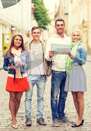 Image of group of smiling friends with map and photocamera