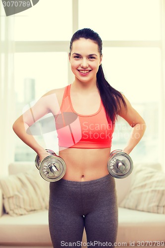 Image of smiling girl exercising with dumbbells