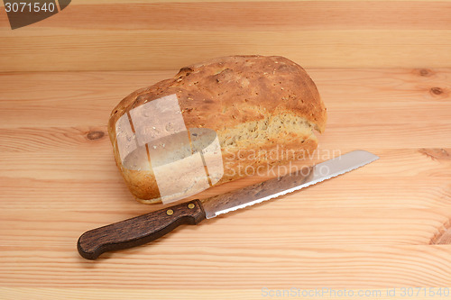 Image of Fresh loaf of oat and linseed bread with a bread knife