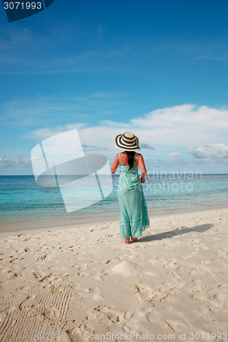 Image of Girl walking along a tropical beach in the Maldives.