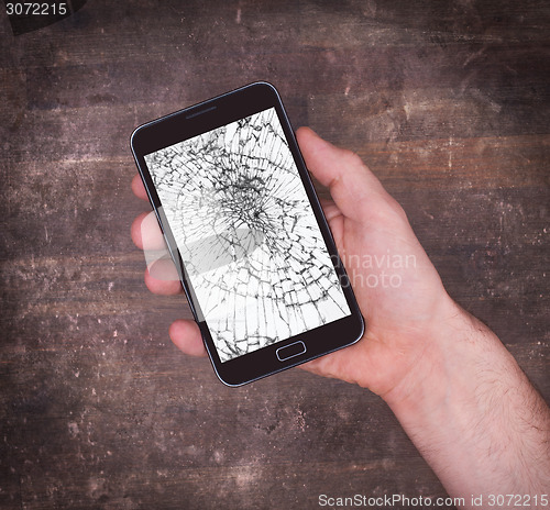 Image of Hand holding a mobile phone with a broken screen