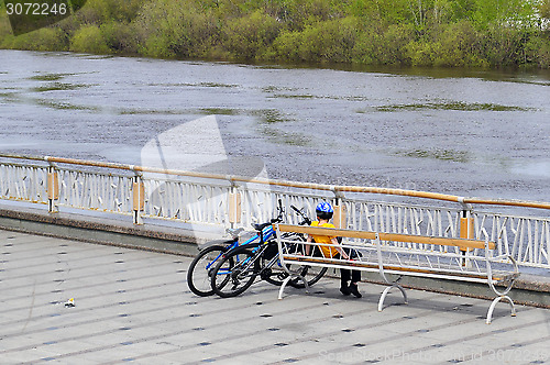 Image of The boy with two bicycles sits on a shop on the embankment in Ty