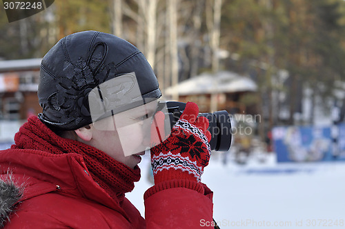 Image of The woman in winter clothes photographs the SLR camera.